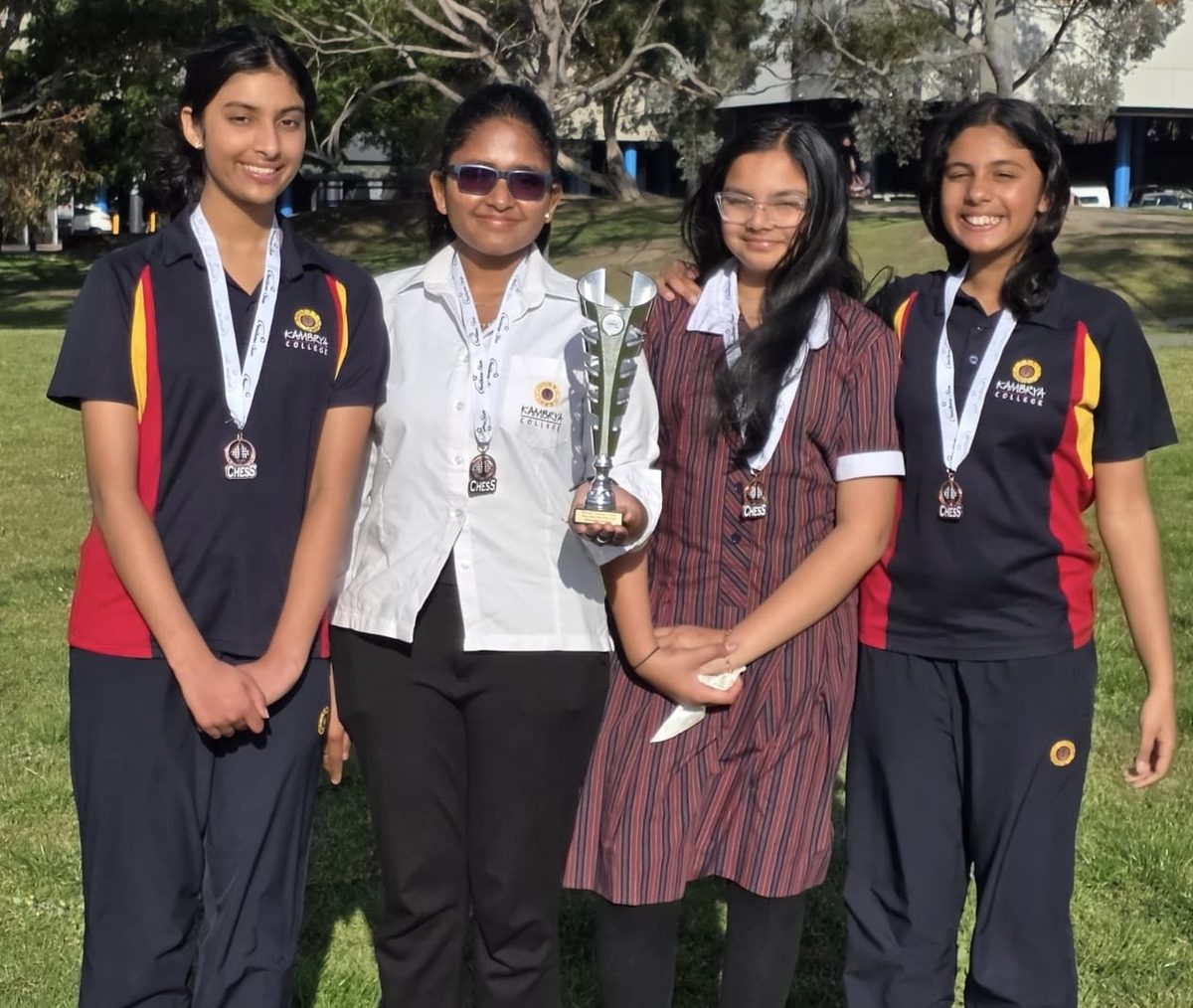 An Oz Chess Kids team holding a championship trophy and medals