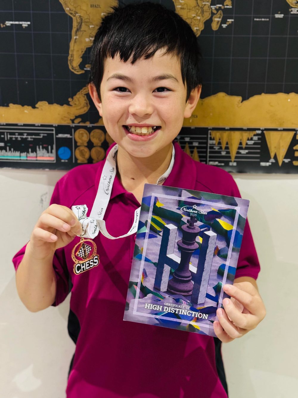 A smiling student with a chess medal and High Distinction certificate