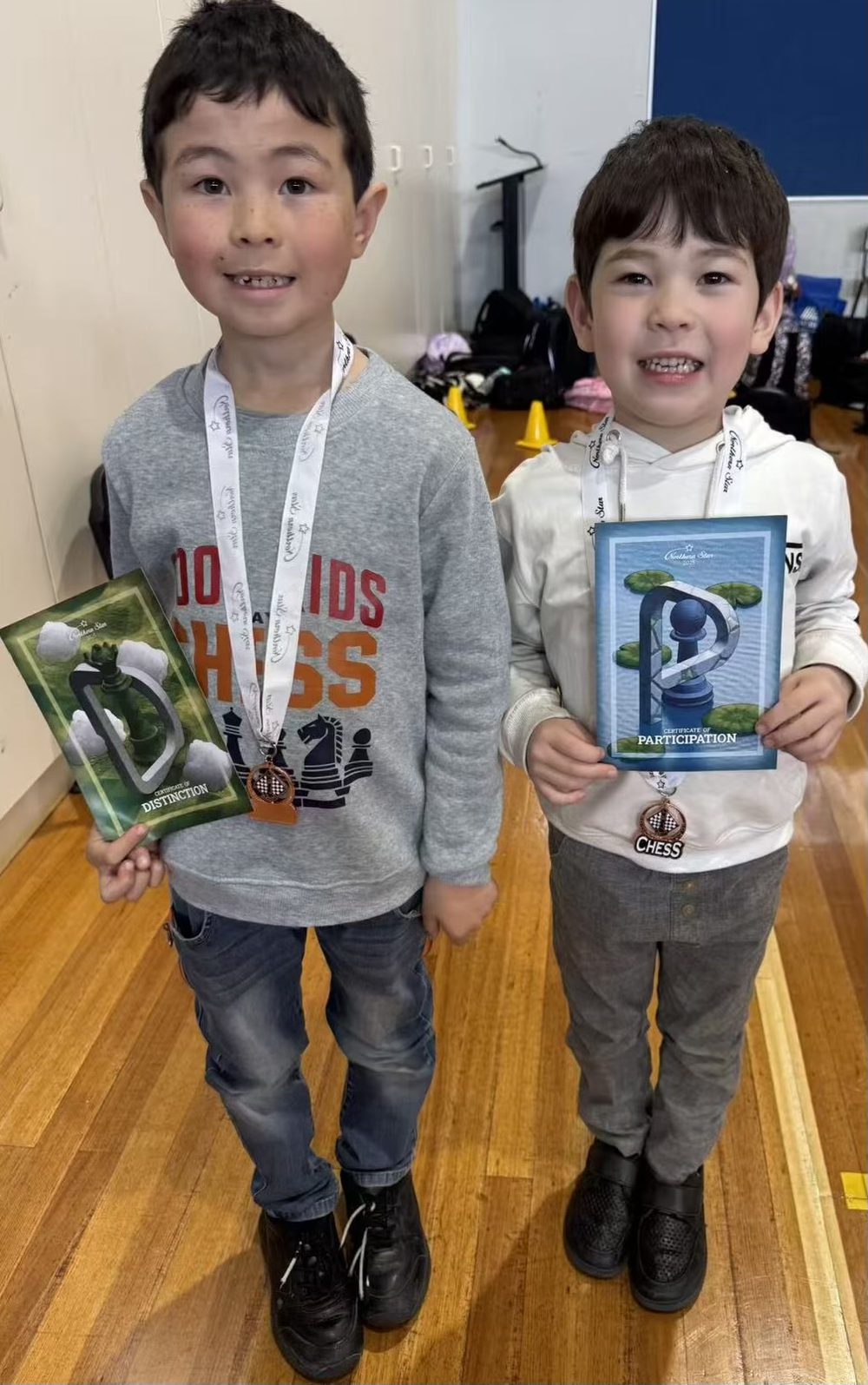 Two young Oz Chess Kids students with medals and certificates