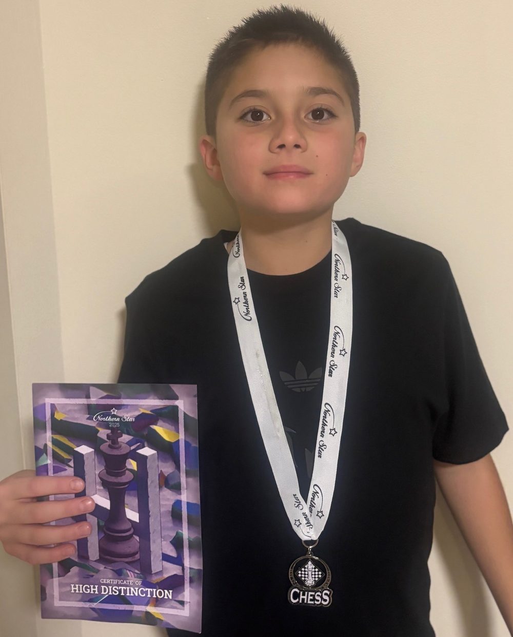 A student with a chess medal and High Distinction certificate