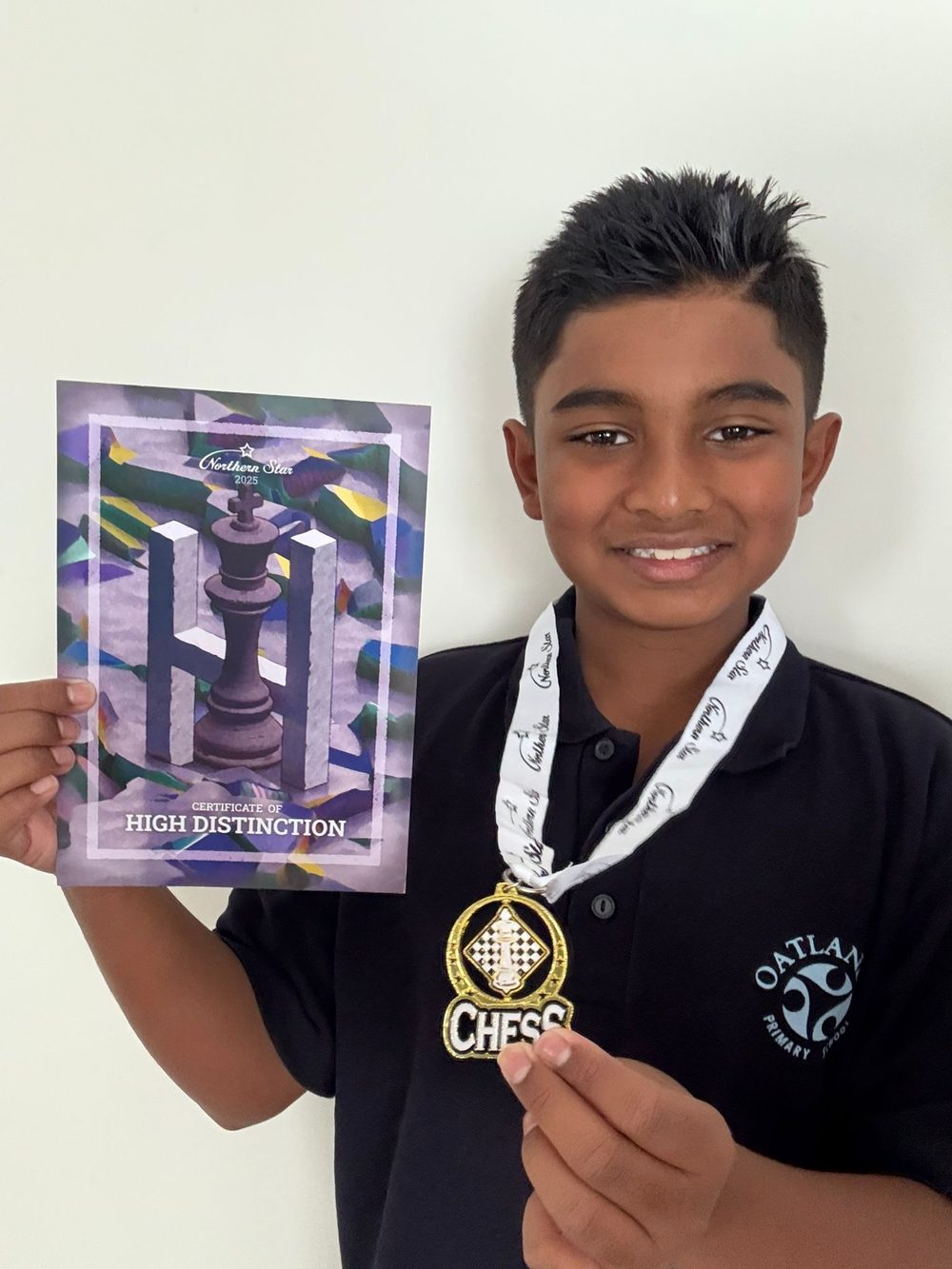 An Oatlands Primary student with a chess medal and High Distinction certificate